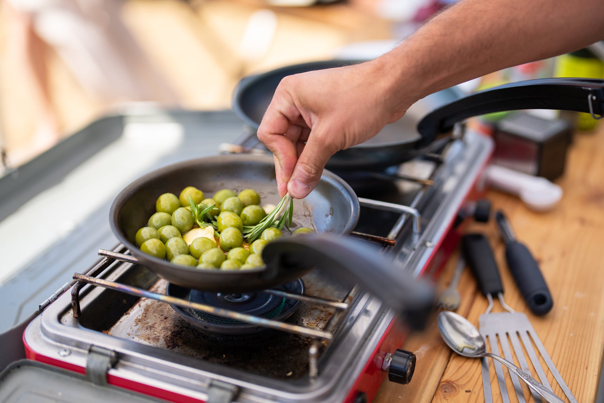 Marinated olives being cooked in carbon steel camp cookware