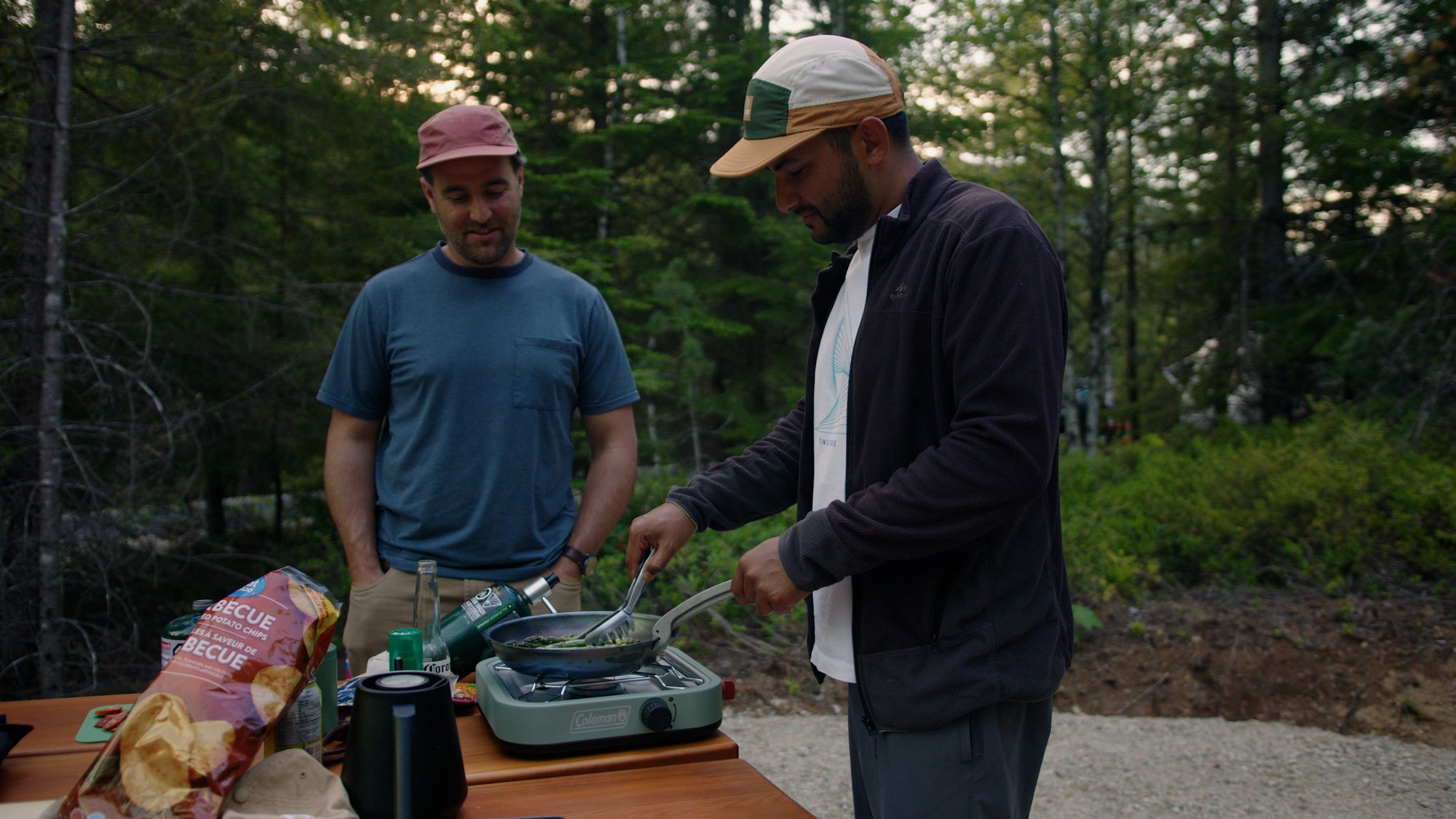 two attractive young men cooking  a meal on a camp stove in a campground