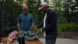 two attractive young men cooking  a meal on a camp stove in a campground