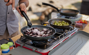 Carbon steel camp cookware with onion and  olives cooking for  dip